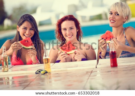 beautiful smiling girls posing by the  swimming pool with slice of watermelon