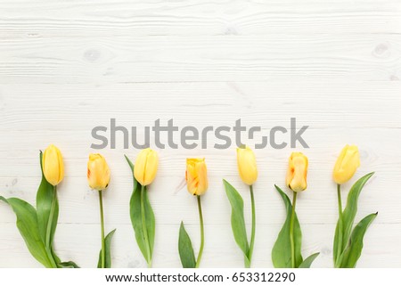 yellow tulips isolated on a white, wooden background. lay flat, top view