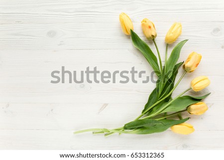 yellow tulips isolated on a white, wooden background. lay flat, top view