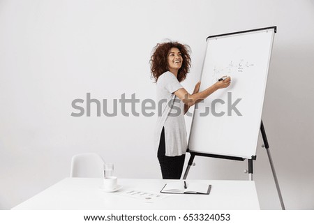 African girl smiling writing on white marker board.