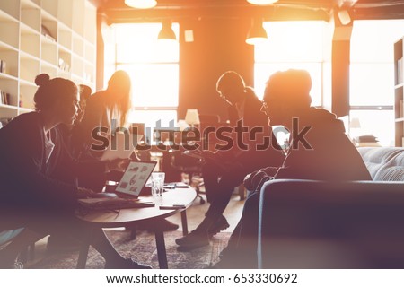 Silhouette of startup team. Meeting on the couch. Big open space office. Five people. Intentional sun glare Royalty-Free Stock Photo #653330692