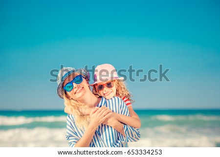 Happy family on the beach. People having fun on summer vacation. Mother and child against blue sea and sky background. Holiday travel concept