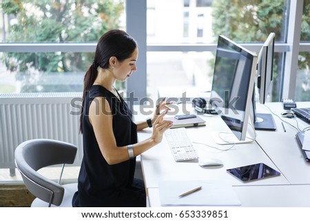 Confident attractive female editor preparing for typing text of article on keyboard of modern computer sitting in loft interior office, businesswoman working online with documentation using wifi