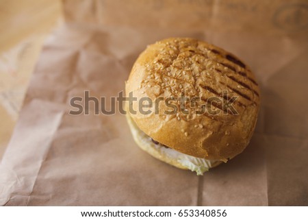 fresh Burger, nice chicken and textured bun with sesame seeds on paper texture. the wooden table. the image for the desktop, menus, and labels in different font