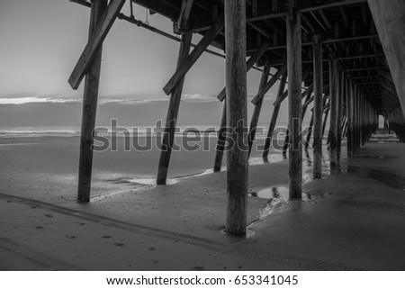Black and white view of the beach from under the Myrtle Beach fishing pier in the early morning 
