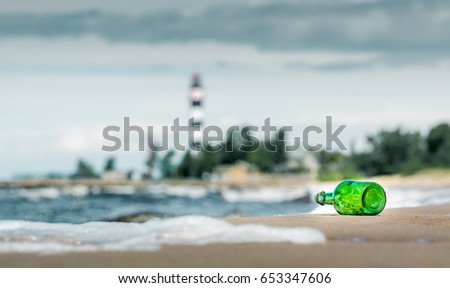 Message in the bottle. A stormy day at the beach with green bottle laying on the coastline
