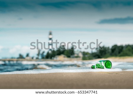 Message in the bottle. A stormy day at the beach with green bottle laying on the coastline
