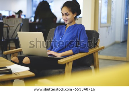 Smiling afro american copywriter working freelance at modern laptop device connecting to free high speed internet connection.Cheerful student chatting online with friends on computer during free time