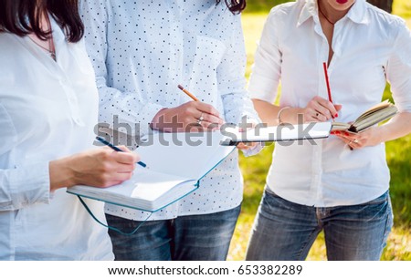 Young beautiful girls drawing the pictures in sketchbook. At the park