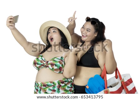 Two fat women taking selfie photo with smartphone, isolated on white background 