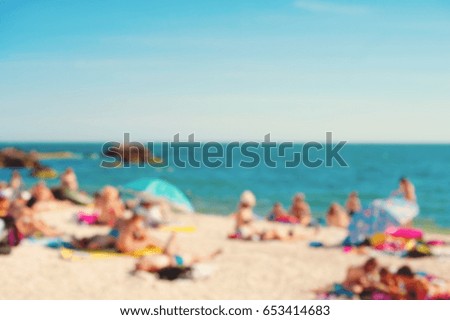 Intentionally out of focus image of people relaxing and having fun at a beach with colorful sun umbrellas