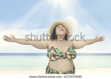 Obese woman wearing straw hat, relaxing on the beach 