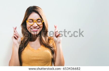 Young woman crossing her fingers and wishing for good luck Royalty-Free Stock Photo #653436682