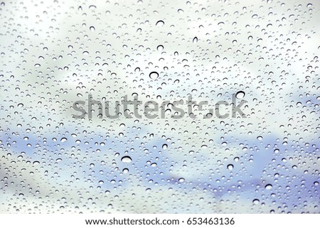 Raindrops on glass under the blue sky background.