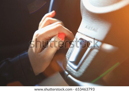 Fingers with pink manicure on steering wheel. Vivid pink nails close-up.