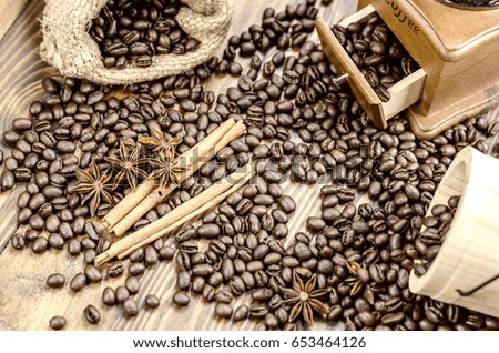Coffee beans on a wooden table, coffee grinder, cinnamon sticks and anise flowers,wooden spoon.