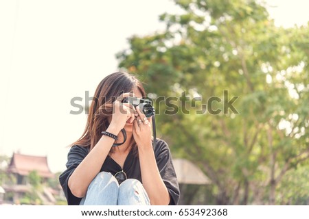 Hipster woman taking photos with retro film camera in outdoor city park,beautiful girl photographed in the old camera