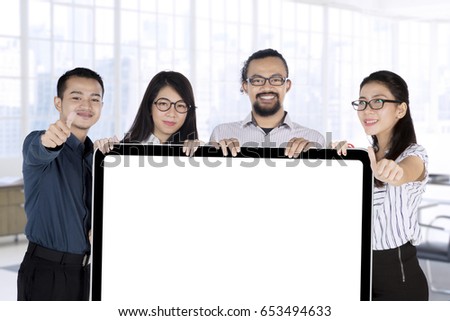 Group of multiracial business team holding a blank placard while showing thumbs up in the office