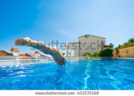 Woman in swimsuit jumping into swimming pool