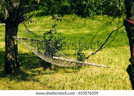 Relaxing lazy time with hammock in the green forest. Beautiful landscape with swinging hammock in the summer garden, sunny day outdoors. Travel, adventure, camping gear, nature outdoors items.
