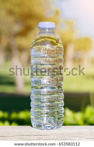 Bottle with fresh clean water on a blurred green grass background vertical picture