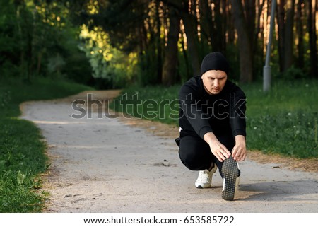 A man is doing exercises preparing for morning workout in a green park on a summer morning copy space