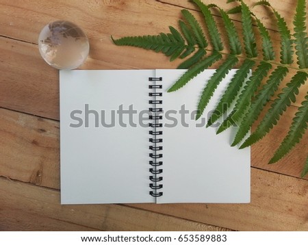 notebook, glass global and leaf on wood background, Element of this image are furnished by NASA