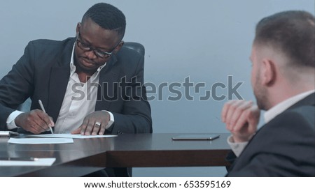 Black businessman signs a contract and gives papers to a partner
