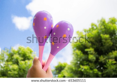 Maracas music  in hand on blurred tree and sky background 