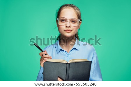 Woman with glasses, notebook with pen holds a woman on a green background                               