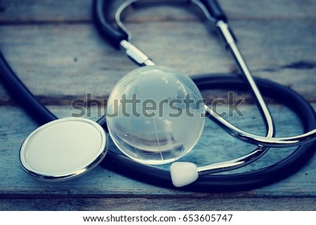 close up glass global and stethoscope on old wood background, world environment day and healthcare concept, process vintage tone. Element of this image are furnished by NASA