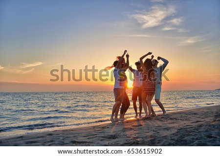 group of happy young people dancing at the beach on beautiful summer sunset Royalty-Free Stock Photo #653615902