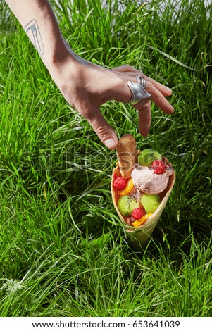Fruit ice cream in waffle cone on grass background