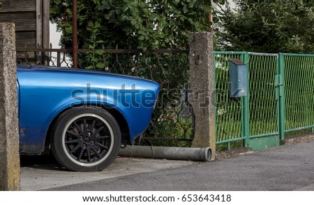 An old blue car in the yard, surrounded by plants, vintage car 