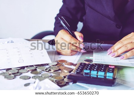  business woman hand calculating her monthly expenses during tax season with coins, calculator, credit card and account bank, idea for dept collection background  Royalty-Free Stock Photo #653650270