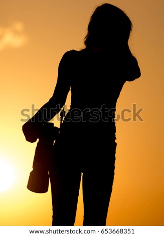 Silhouette of a girl photographer at sunset