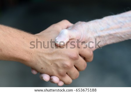 Old and young man shaking or gripping hands in a close up view conceptual of assistance, agreement, acceptance, greeting and tolerance