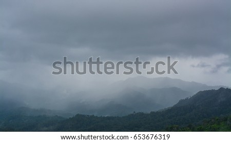 Dark mountain landscape with dramatic sky and raining