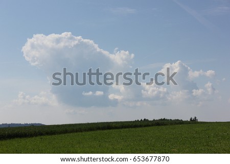 on a very sunny day in june in south germany you see summer cumulus clouds above landscape that bring together green of lawn with blue sky and sunshine