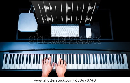 music production technology, male composer hands working on piano keys with computer on desk