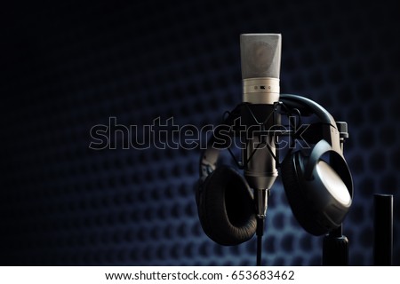 Studio microphone and headphones on mic stand against gray background Royalty-Free Stock Photo #653683462