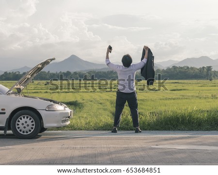 Young business man having trouble with his broken car 