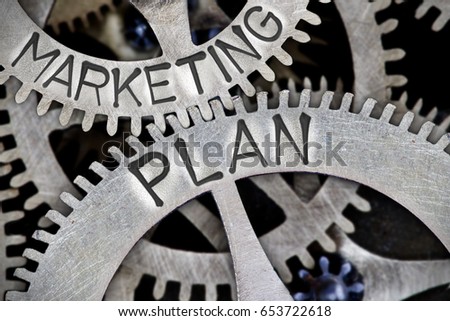 Macro photo of tooth wheel mechanism with MARKETING PLAN letters imprinted on metal surface