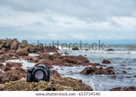 Photographer demo waterproof for DSLR camera and tele lens by wet from water sea wave at beach when travel and test using in the extreme environment