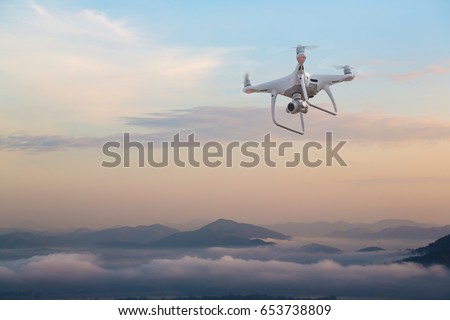 UAV drone copter flying with digital camera.Drone with high resolution digital camera. Flying camera take a photo and video.The drone with professional camera takes pictures of the misty mountains.