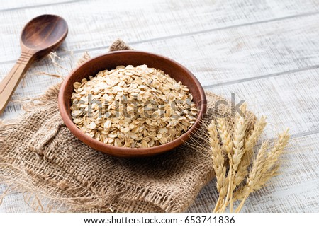Rolled oats, healthy breakfast cereal oat flakes in bowl on wooden table Royalty-Free Stock Photo #653741836