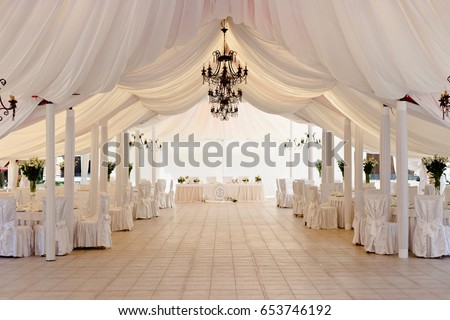 Marquee for the celebration of the wedding. Beautiful white interior with white draperies Royalty-Free Stock Photo #653746192
