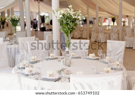 Wedding ceremony decoration in the restaurant. Decoration of wedding table with tender white textile. Elegant cafe decoration