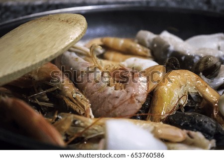 Preparing seafood for paella in restaurant frying pan, food