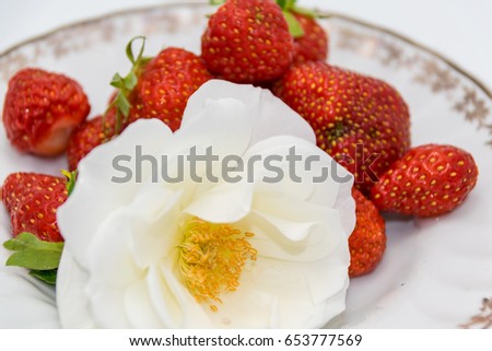 strawberries and a white rose on a small plate